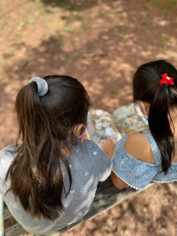 Two early elementary students read a book in an outdoor garden.